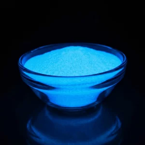 Glowing blue powder in a clear glass bowl against a dark background